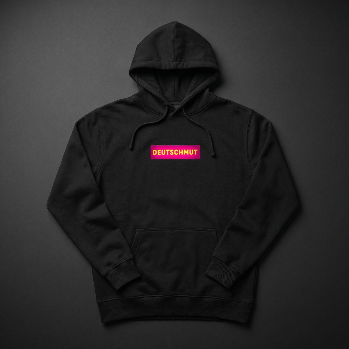 Box-Logo Hoodie: schwarzer Hoodie mit gesticktem Box-Logo — gelber DEUTSCHMUT-Schriftzug auf Magenta, wie auf dem Buchcover